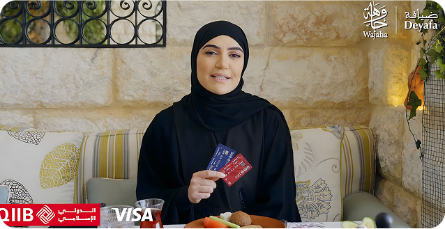 Woman holding QIIB and Visa cards with food items